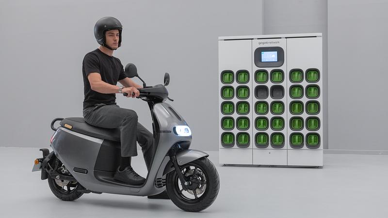 A Gogoro rider in his Smartscooter with a GoStation in the background.